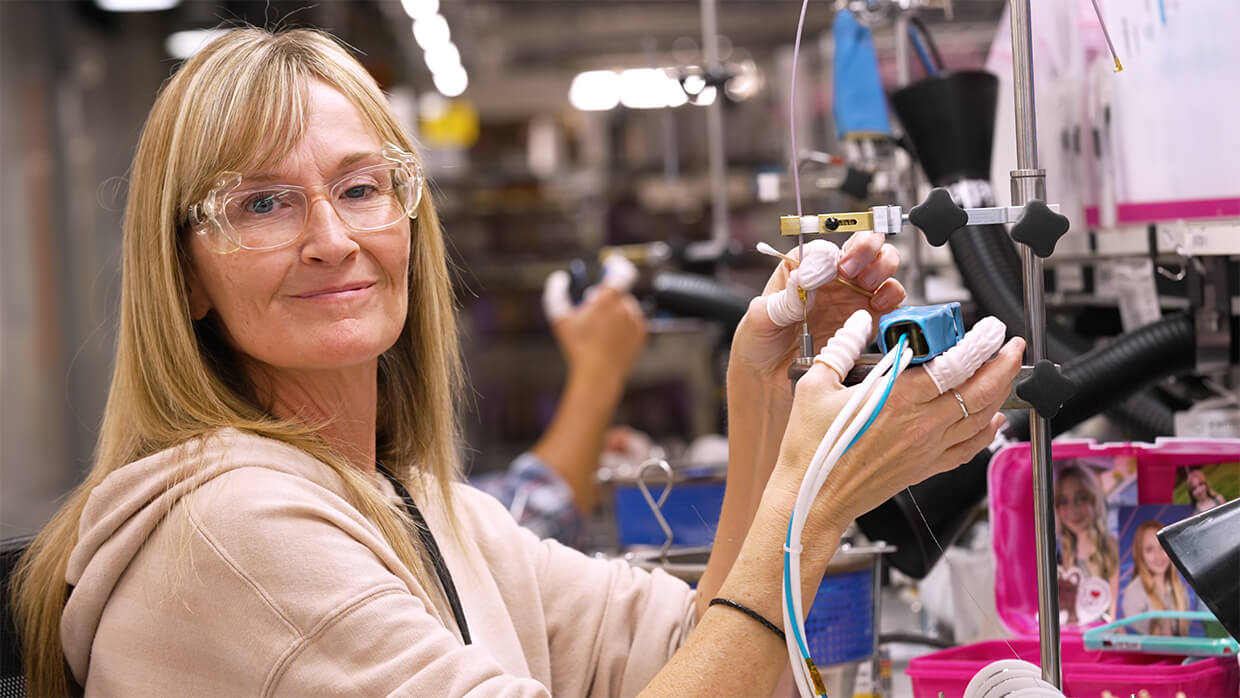 Gore Associate wearing safety glasses and gloves working with wiring at an assembly station.